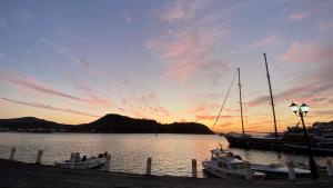 two boats docked at a dock with a sunset at Skala Hotel in Skala