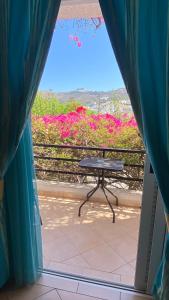 a balcony with a table and a view of flowers at Skala Hotel in Skala