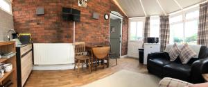 a living room with a couch and a brick wall at Nanny Goat Rest At Ashlands Farm in Abbots Bromley