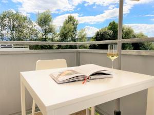 einen weißen Tisch mit einem Buch und ein Glas Wein in der Unterkunft Holiday Suites Sankt Martin in Klagenfurt am Wörthersee