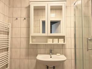 ein weißes Badezimmer mit einem Waschbecken und einem Spiegel in der Unterkunft Holiday Suites Sankt Martin in Klagenfurt am Wörthersee