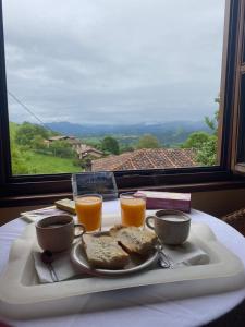 una bandeja con un plato de comida y dos vasos de zumo de naranja en Casa Tenada, en Robledo