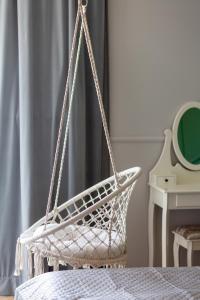 a white basket chair in a bedroom with a bed at Amsterdam Estate Apartments Rembrandta in Warsaw