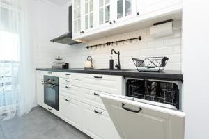 a kitchen with white cabinets and a dishwasher at Amsterdam Estate Apartments Rembrandta in Warsaw