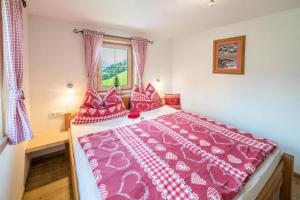 ein Schlafzimmer mit einem großen Bett mit rosa Bettwäsche und einem Fenster in der Unterkunft Biohof Vorderreith in Jochberg