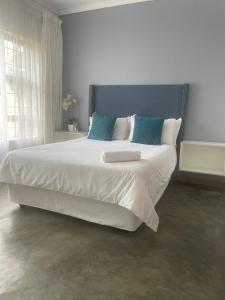 a bedroom with a large white bed with blue pillows at Maso palace in Polokwane