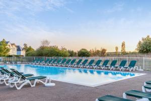 a swimming pool with lounge chairs and a fence at Résidence Pierre & Vacances Le Domaine de Bourgenay in Talmont +91 photos
