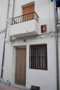 Edificio blanco con balcón y puerta en CASICA TIA CARMEN, en Chulilla