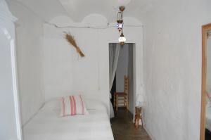 1 dormitorio blanco con 1 cama y 1 silla en CASICA TIA CARMEN, en Chulilla