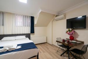 a bedroom with a bed and a table and a tv at Asteria House in Istanbul