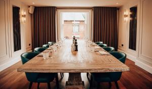 uma mesa longa num quarto com cadeiras verdes em Lion & Swan Hotel em Congleton