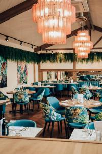 um restaurante com cadeiras e mesas azuis e lustres em Lion & Swan Hotel em Congleton