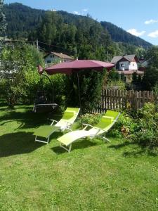 two lawn chairs and an umbrella in a yard at Gästehaus Maria in Steinach am Brenner