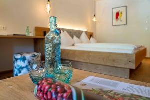 einen Tisch mit Brille, eine Flasche und ein Bett in der Unterkunft Das Leonhard - Naturparkhotel am Weissensee in Weissensee