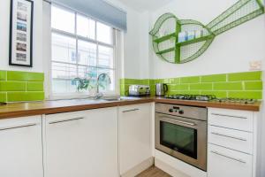 una cocina con armarios blancos y azulejos verdes en Cannon Place - Central - by Brighton Holiday Lets, en Brighton & Hove
