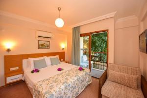 um quarto com uma cama, uma cadeira e uma janela em Perdikia Hill Hotel And Villas em Oludeniz