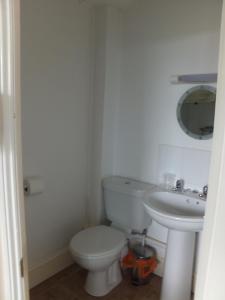Baño blanco con aseo y lavamanos en Sea Jade Guest House, en Bude
