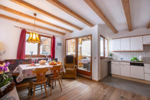 Una cocina y un comedor con mesa y sillas. en Binterhof ROSALPINA APP, en Castelrotto