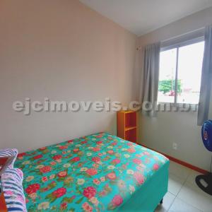 a bedroom with a bed with a floral bedspread and a window at Casa na Praia Guaratuba - Brejatuba in Guaratuba