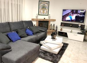 a living room with a couch and a television at 4 bedrooms villa with private pool enclosed garden and wifi at Olocau in Olocau