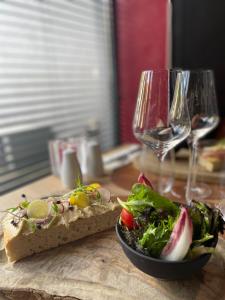 a table with a sandwich and a salad and wine glasses at Martin's Dream Hotel in Mons