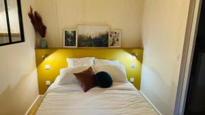 um quarto com uma cama com lençóis brancos e almofadas em Legend - Parking privé - Gare - Centre ville - Quai de Saône - fibre em Mâcon