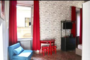 ローマにあるPantheon Palazzo Lanziの赤いカーテン、赤い椅子とテーブルが備わる客室です。