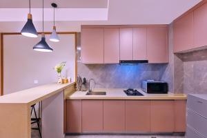 a kitchen with pink cabinets and a sink at Mayu Valley Hot Spring Homestay in Tengchong
