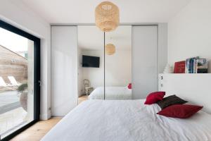 una camera da letto con un grande letto bianco con cuscini rossi di Maison Le Clos Neraud avec piscine et SPA a Saint-Martin-de-Ré