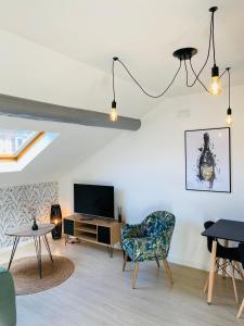 a living room with a tv and a chair and a table at le Seize B in Épernay