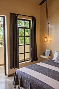 um quarto com uma cama e uma janela em Botånica Tulum em Tulum