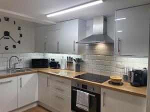 a kitchen with white cabinets and a stove top oven at The Garden Apartment in Newton Abbot