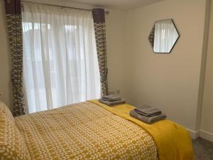 a bedroom with a bed with a yellow blanket and a window at The Garden Apartment in Newton Abbot