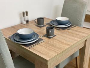 a wooden table with three cups and plates on it at The Garden Apartment in Newton Abbot