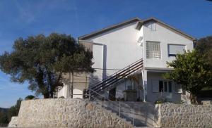 a white house on top of a stone wall at Apartment Kampor 3 in Kampor