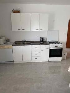 a kitchen with white cabinets and a stove top oven at Apartment Kampor 2 in Kampor