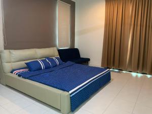 a bedroom with a bed with a blue blanket and a chair at Woon Homestay in Balik Pulau