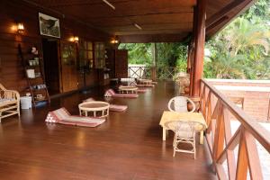 a porch with chairs and tables on a wooden floor at Ashi Guesthouse Chiangdao in Chiang Dao