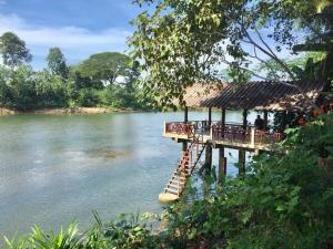a pier with tables and chairs on a river at Ratmanee House in Kanchanaburi City