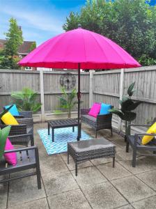 - un parasol rose sur une terrasse avec des chaises et des tables dans l'établissement 'Number 11' Central Colchester - Super Convenient 2 x Double Bed 1 x Single Bed Cottage PLUS Office & Garden, 8 min walk Nth Station & Town Ctr, 2 min walk local shops & restaurants, à Colchester