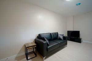 a black leather couch in a living room with a tv at Alpha Lofts, Huddersfield in Huddersfield