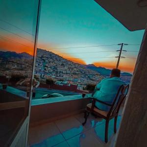 un hombre sentado en una silla viendo la puesta de sol en Over Mountains Hotel, en Wadi Musa