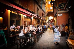 een groep mensen aan tafel in een steegje bij Urbanicooh San Petronio - Torre Asinelli view in Bologna