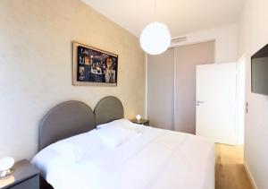 カンヌにあるViva Riviera - Modern Brand New 1 Bedroom Palais Fochの白いベッドと壁の絵が備わるベッドルーム1室が備わります。