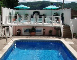 a house with a swimming pool and a balcony with chairs and umbrellas at Windsor Motel in Lake George