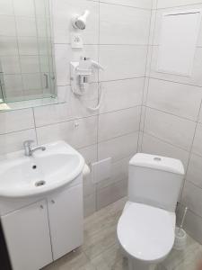 a white bathroom with a toilet and a sink at Hotel Relax in Kirov