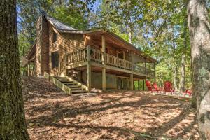 a log cabin in the woods with red chairs at Blue Ridge Cabin Hot Tub, Fire Pit and Grill! in Blue Ridge