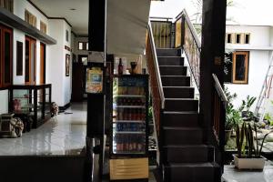 Ngawinan的住宿－Dinnar Homestay Gayungan Mitra RedDoorz，一间设有楼梯的房间,有饮料架