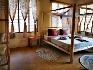 um quarto com uma cama de dossel num quarto com janelas em Shanka Lodge Zanzibar em Kizimkazi