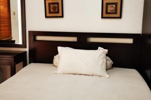 łóżko z białą pościelą i poduszkami w sypialni w obiekcie Dinnar Homestay Gayungan Mitra RedDoorz w mieście Ngawinan